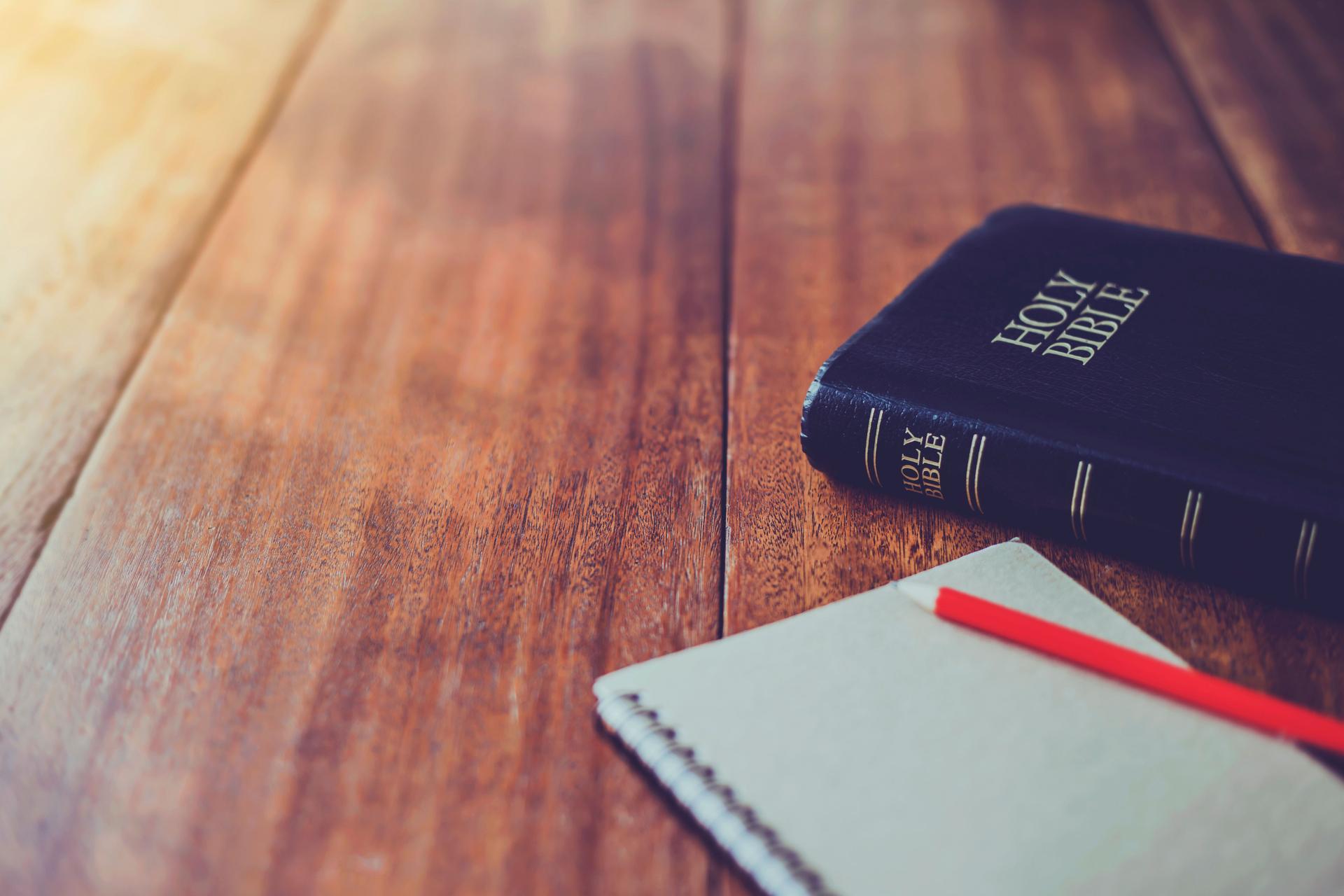 Holy bible with note book and pencil on wooden table against morning  sun light for christian devotion, copy space